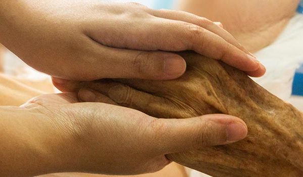 Person holding the hand of someone in the hospital