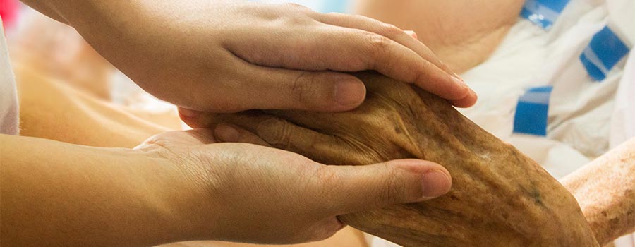 Person holding the hand of someone in the hospital