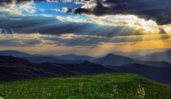 Landscape photo of mountains with the sun poking through the clouds