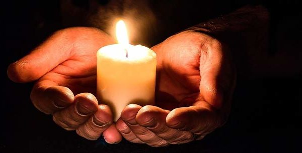 Person holding a candle in their hands in a dark room