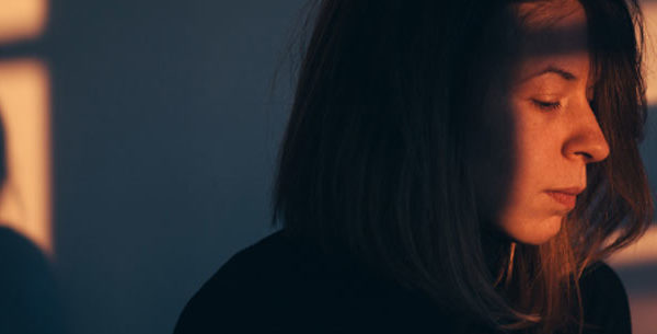 Woman looking down grieving in sunlit room