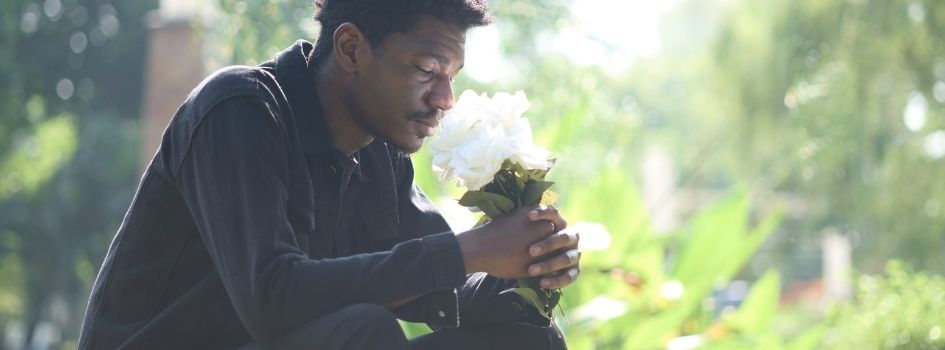 man grieving at gravesite